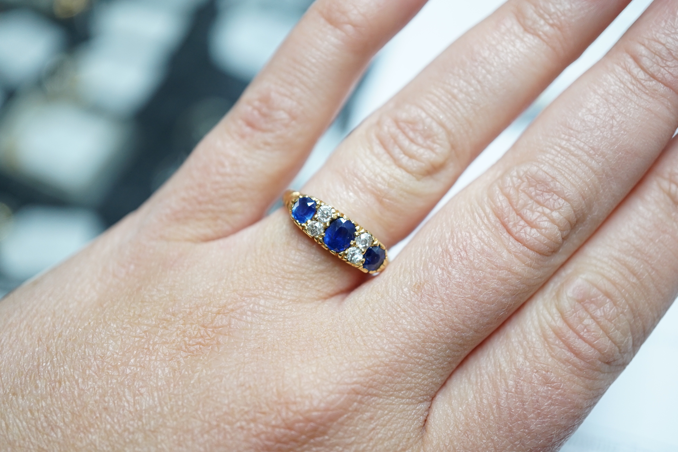 A late Victorian 18ct gold and three stone sapphire set ring, with four stone diamond set spacers, size M, gross weight 4.1 grams.
